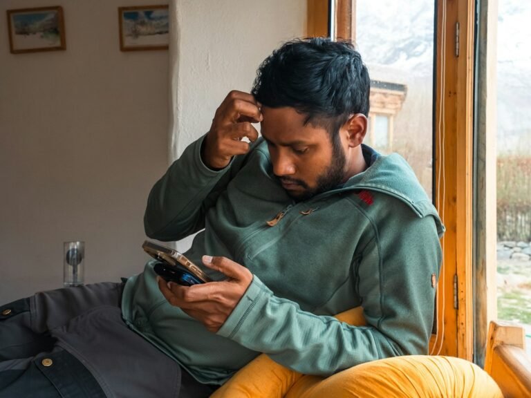 Adult looking thoughtfully at a phone while taking a pause from dating apps